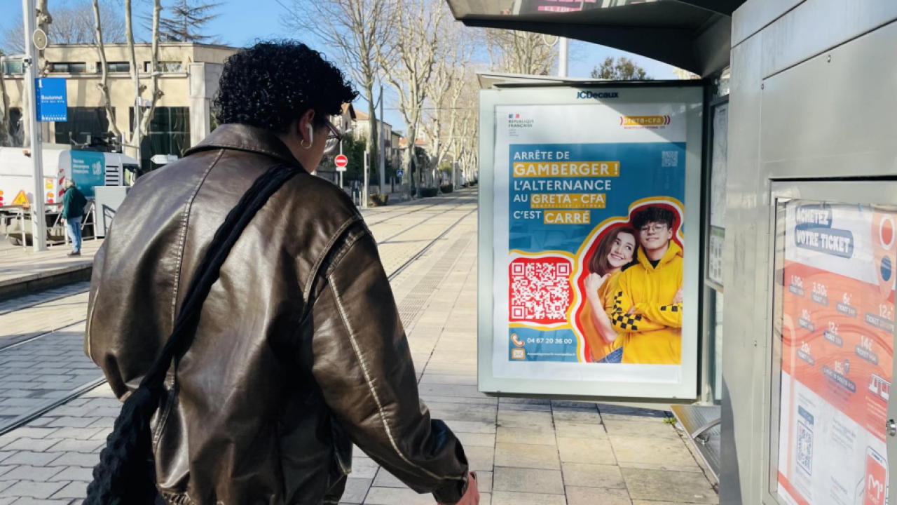 Un homme marche ver sune affiche publicitaire du GRETA CFA MONTPELLIER LITTORAL